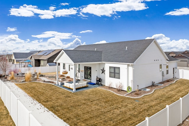 rear view of house featuring a yard, a fenced backyard, a residential view, and a shingled roof