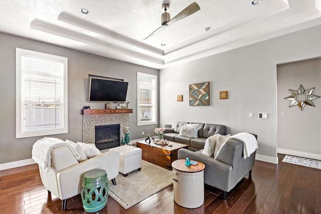 living room with baseboards, a tray ceiling, and dark wood-style flooring