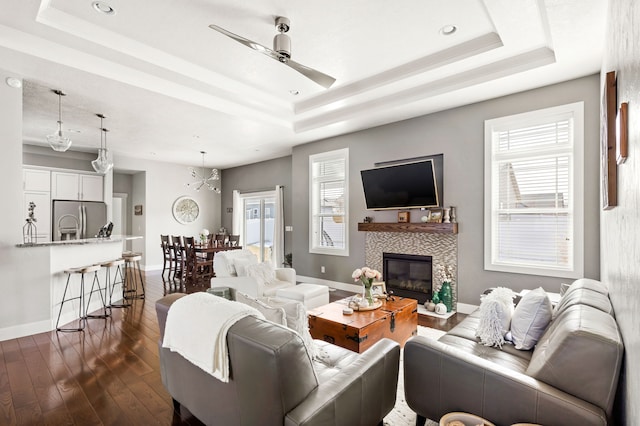 living area featuring a raised ceiling, plenty of natural light, and dark wood finished floors