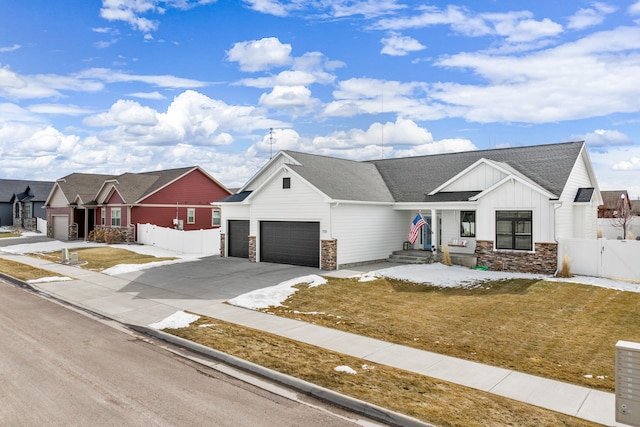 view of front of home with a gate, fence, concrete driveway, stone siding, and board and batten siding