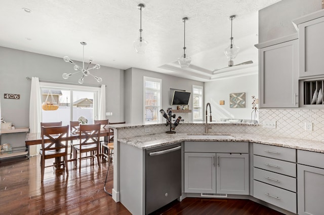 kitchen with gray cabinetry, a sink, a peninsula, a raised ceiling, and dishwasher