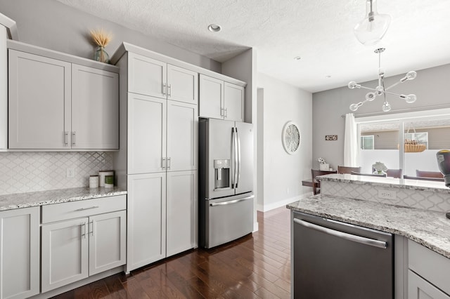 kitchen with dark wood-type flooring, backsplash, a textured ceiling, stainless steel appliances, and hanging light fixtures