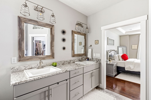 ensuite bathroom featuring double vanity, wood finished floors, ensuite bath, and a sink