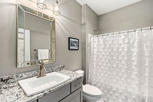 bathroom with a shower with shower curtain, toilet, and vanity