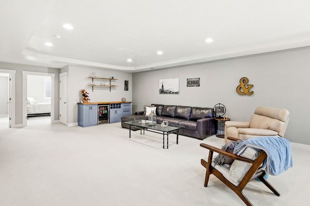 living area with recessed lighting, light colored carpet, a raised ceiling, and a bar