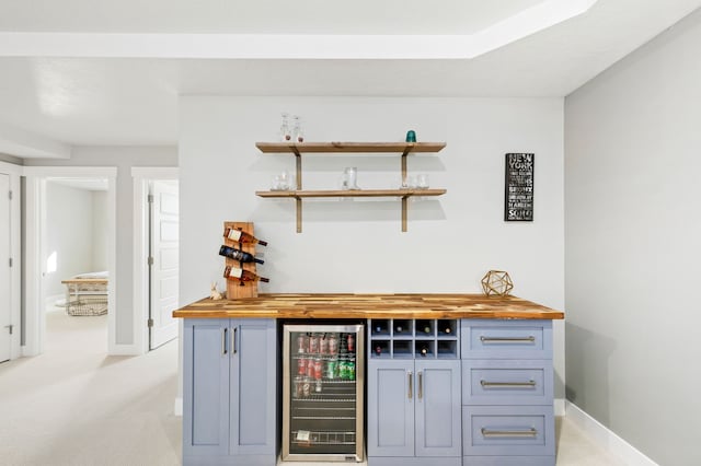 bar featuring beverage cooler, light colored carpet, a dry bar, and baseboards