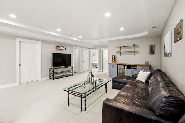 living room featuring a bar, a tray ceiling, recessed lighting, and visible vents