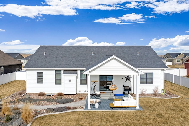 rear view of property featuring a lawn, a fenced backyard, and roof with shingles