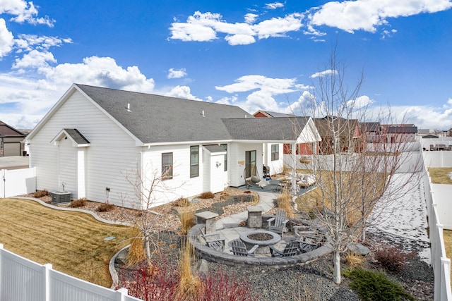 rear view of property featuring cooling unit, an outdoor fire pit, a fenced backyard, a shingled roof, and a patio area