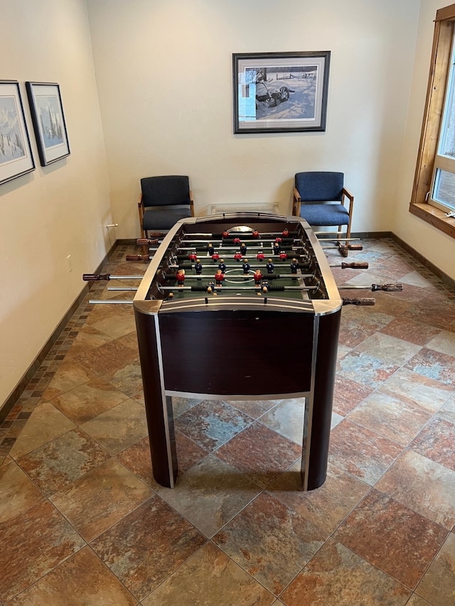 recreation room featuring stone finish floor and baseboards