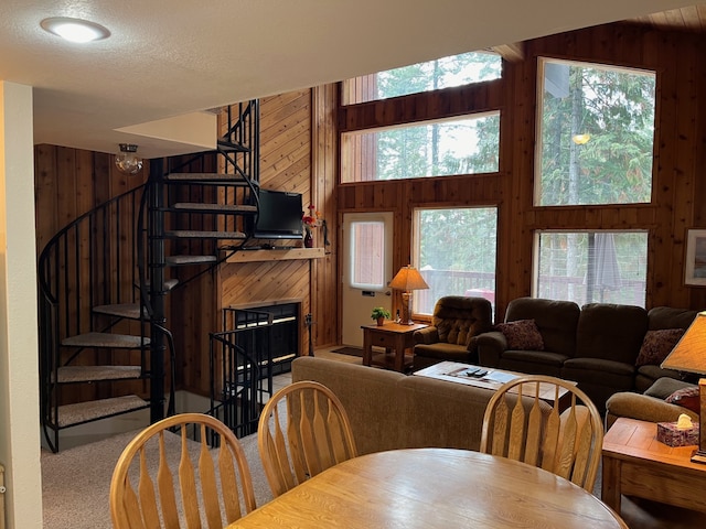 dining space with stairs, wooden walls, carpet flooring, and a healthy amount of sunlight