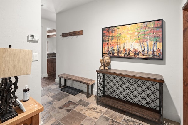 corridor featuring stone finish floor and baseboards