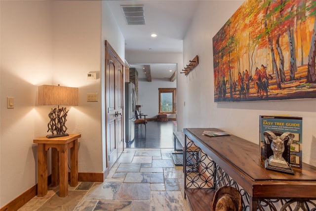 corridor with recessed lighting, visible vents, baseboards, and stone tile floors