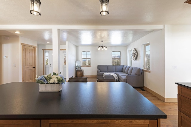 kitchen with light wood-type flooring, baseboards, dark countertops, and a center island