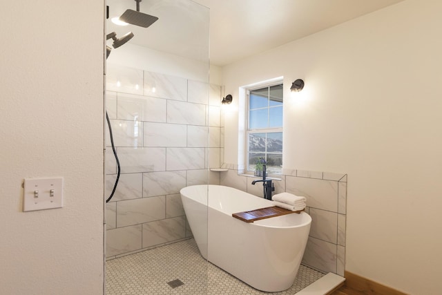 full bath with tiled shower, a freestanding bath, and tile walls