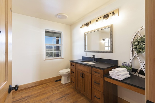 bathroom featuring visible vents, baseboards, toilet, wood finished floors, and vanity