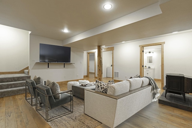 living area with visible vents, hardwood / wood-style flooring, recessed lighting, stairway, and a wood stove