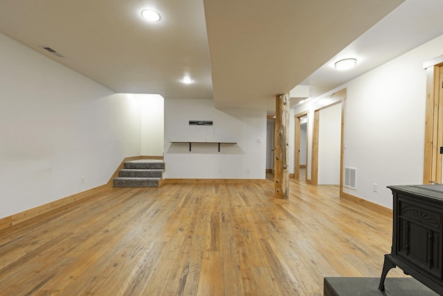 living room featuring visible vents, hardwood / wood-style floors, a wood stove, and stairway