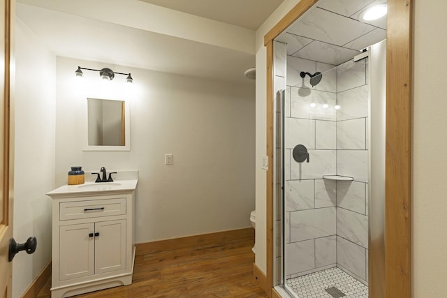 bathroom featuring vanity, wood finished floors, baseboards, a stall shower, and toilet