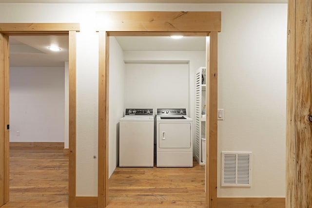 washroom with visible vents, baseboards, laundry area, light wood-style flooring, and washer and dryer