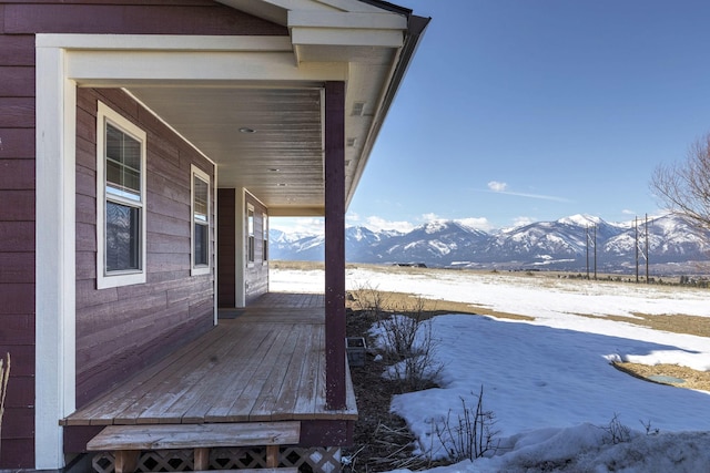 snow covered deck with a porch and a mountain view