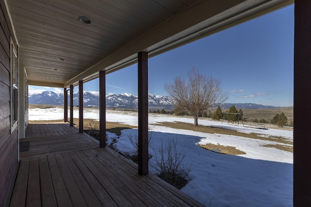 snow covered deck with a mountain view