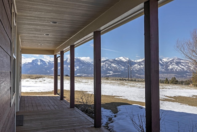 snow covered deck with a mountain view