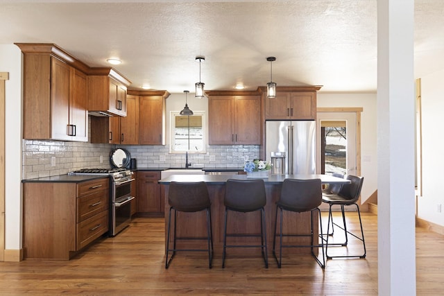 kitchen featuring a wealth of natural light, stainless steel appliances, dark countertops, and wood finished floors