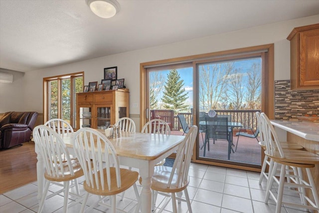 dining space with an AC wall unit and light tile patterned floors