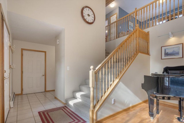 staircase featuring tile patterned floors, baseboards, and a towering ceiling