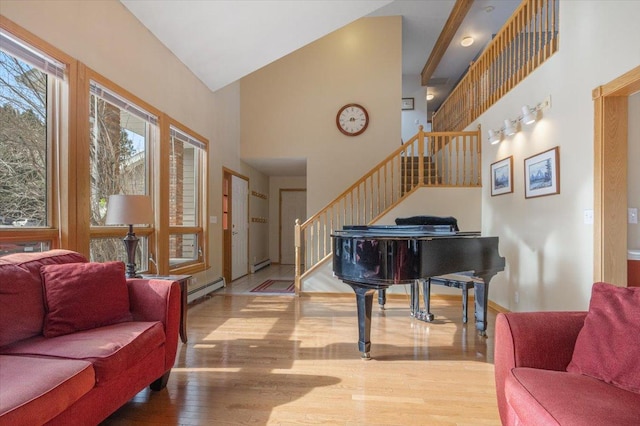 foyer entrance with stairway, baseboard heating, wood finished floors, and high vaulted ceiling