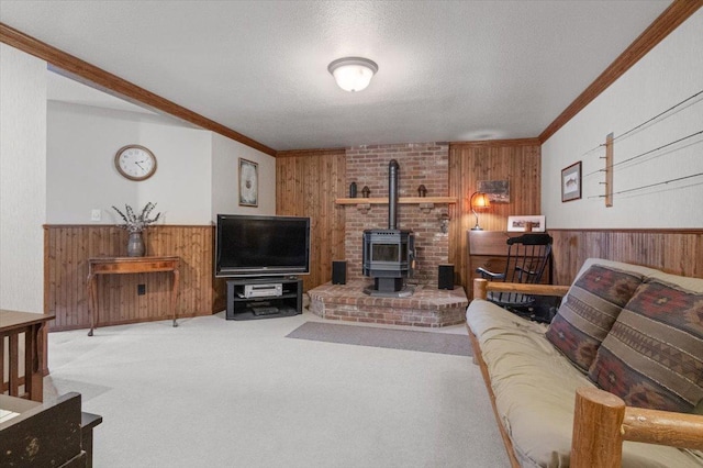 carpeted living room with a wainscoted wall, a textured ceiling, wooden walls, crown molding, and a wood stove