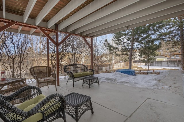 snow covered patio with a fenced backyard