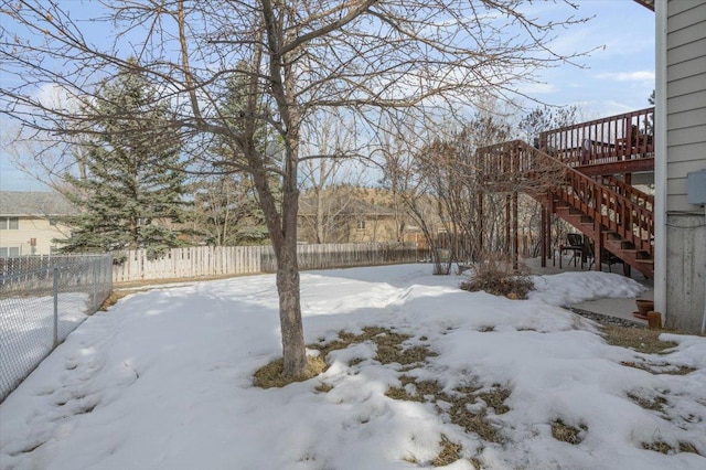 snowy yard featuring a fenced backyard and stairs