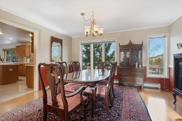 dining space featuring a baseboard heating unit, ornamental molding, light wood-type flooring, and a chandelier