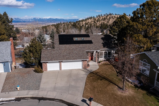 view of front facade featuring brick siding, an attached garage, concrete driveway, a mountain view, and a pergola