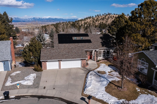 view of front facade with a mountain view, an attached garage, brick siding, and driveway