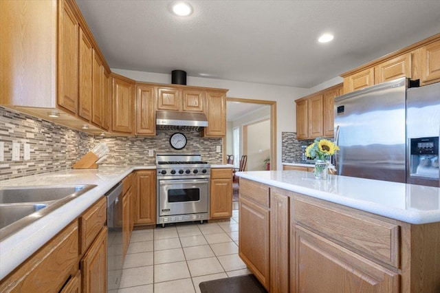 kitchen with under cabinet range hood, light tile patterned floors, appliances with stainless steel finishes, and light countertops