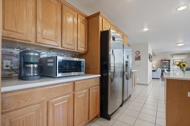 kitchen with open floor plan, stainless steel appliances, light countertops, light tile patterned floors, and decorative backsplash