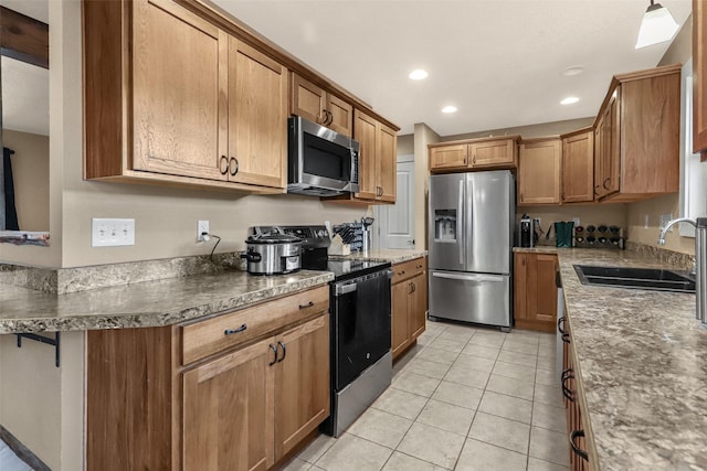 kitchen with brown cabinets, a sink, recessed lighting, appliances with stainless steel finishes, and light tile patterned floors