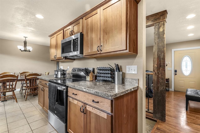 kitchen featuring a textured ceiling, dark countertops, a notable chandelier, and stainless steel appliances