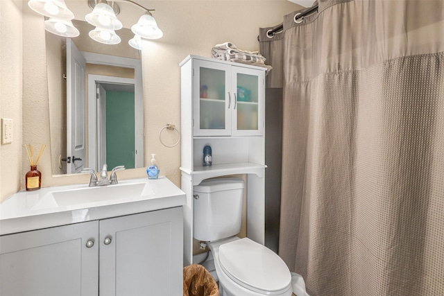 full bath featuring vanity, curtained shower, toilet, and a textured wall