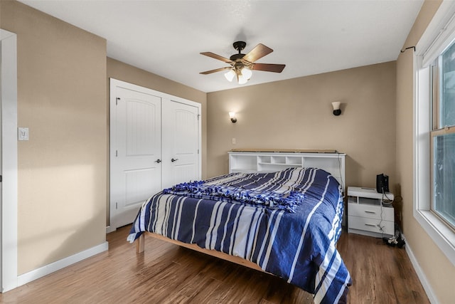 bedroom with multiple windows, wood finished floors, and baseboards