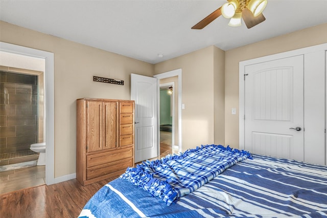 bedroom with ceiling fan, ensuite bath, baseboards, and wood finished floors