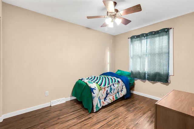 bedroom with visible vents, baseboards, wood finished floors, and a ceiling fan