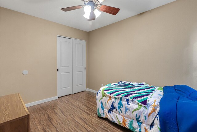 bedroom with a closet, a ceiling fan, baseboards, and wood finished floors