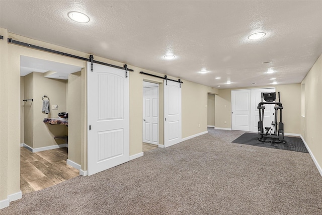 exercise area with baseboards, carpet flooring, a textured ceiling, and a barn door