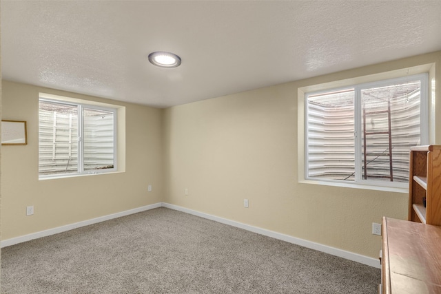 unfurnished room with carpet, baseboards, and a textured ceiling