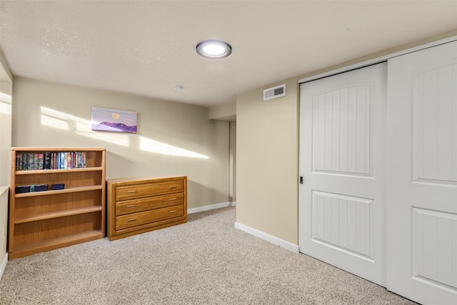 below grade area with visible vents, a textured ceiling, baseboards, and carpet