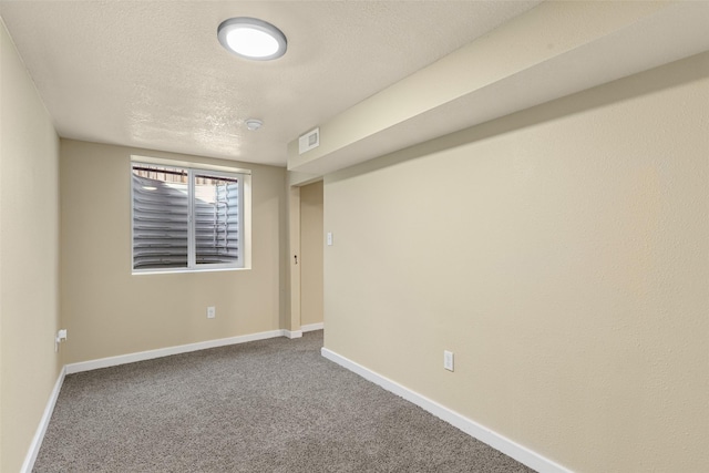 carpeted empty room featuring baseboards, visible vents, and a textured ceiling